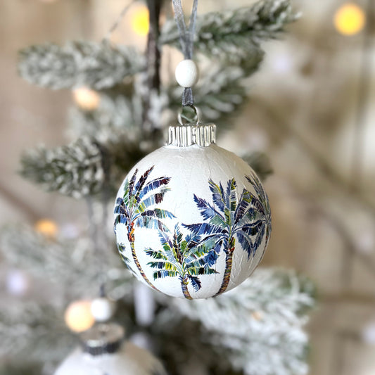 Decorative Christmas ornaments with palm tree patterns hanging on a tree.
