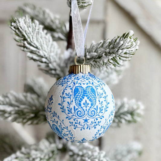 Decorative blue and white ornament on a Christmas tree branch with a wooden background