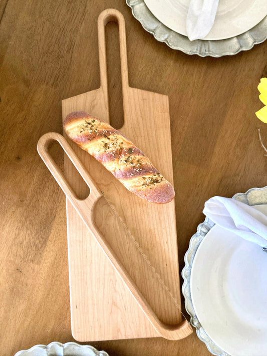 solid maple 2 ft long cutting board displayed with the matching bow bread knife