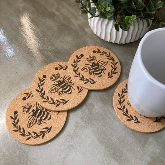 set of 4 bumble bee with crown and surrounded with a laurel of leaves and berries that have been laser engraved on cork