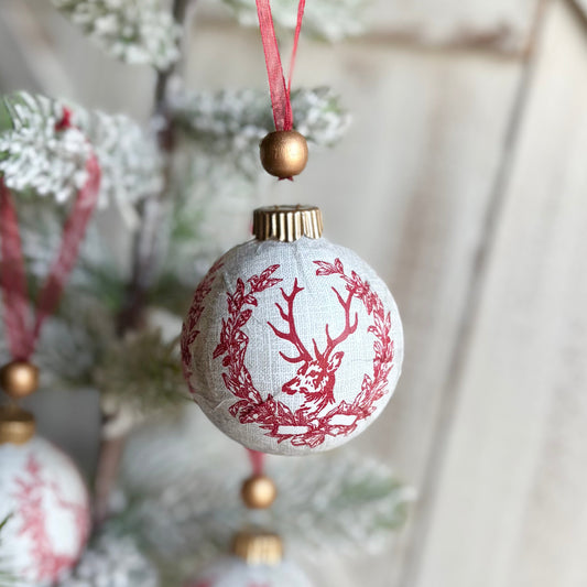 Decorative Christmas ornaments with reindeer design hanging on a tree.
