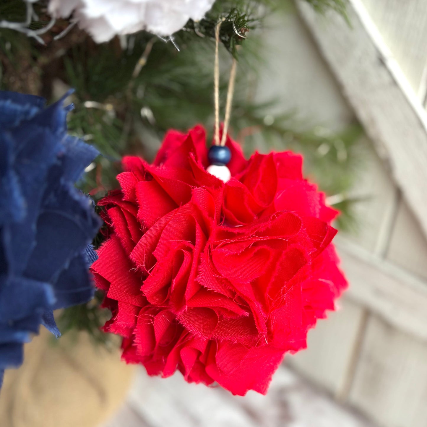 Red and blue decorative balls hanging on a Christmas tree with a white textured background.