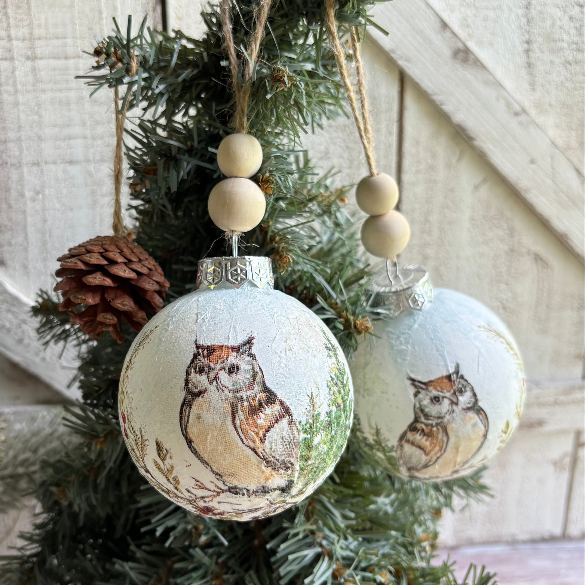 Decorative Christmas ornaments with owl designs hanging on a tree.