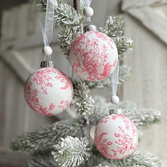 Decorative Christmas tree with pink and white ornaments against a rustic wooden background