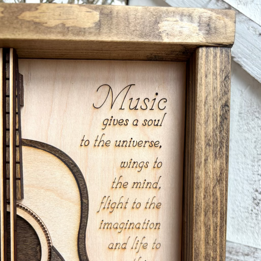 Wooden plaque with guitar design and engraved quote by Plato on a wooden background