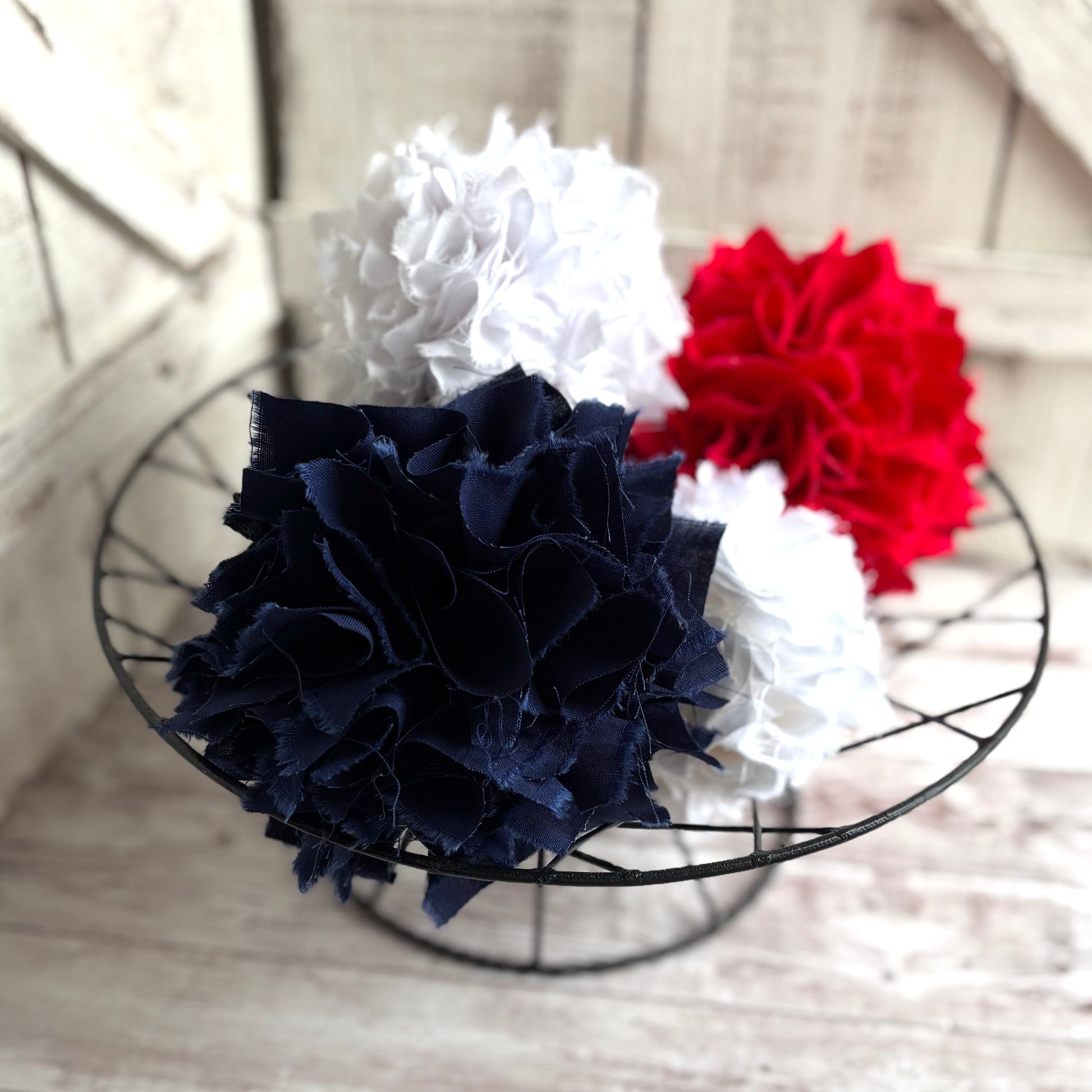 Fabric rag balls in red white and navy in a wire basket for a table top decoration