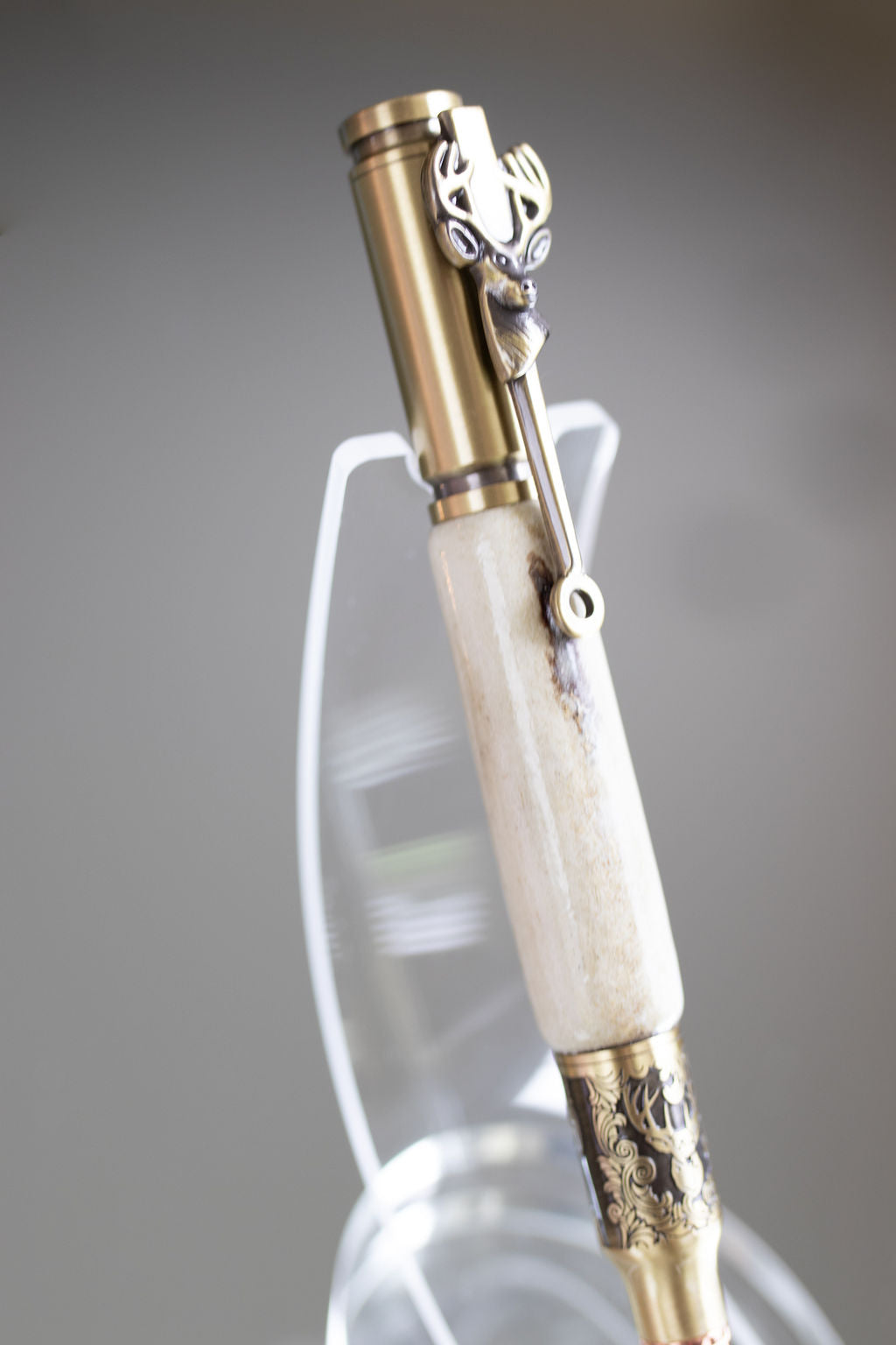 Decorative pen with gold and white accents on a gray background