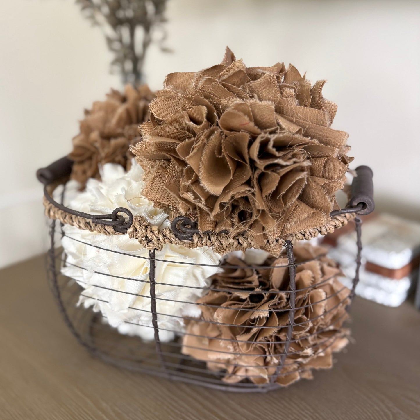 Decorative arrangement of brown textured rag balls  in a wire basket on a wooden surface.