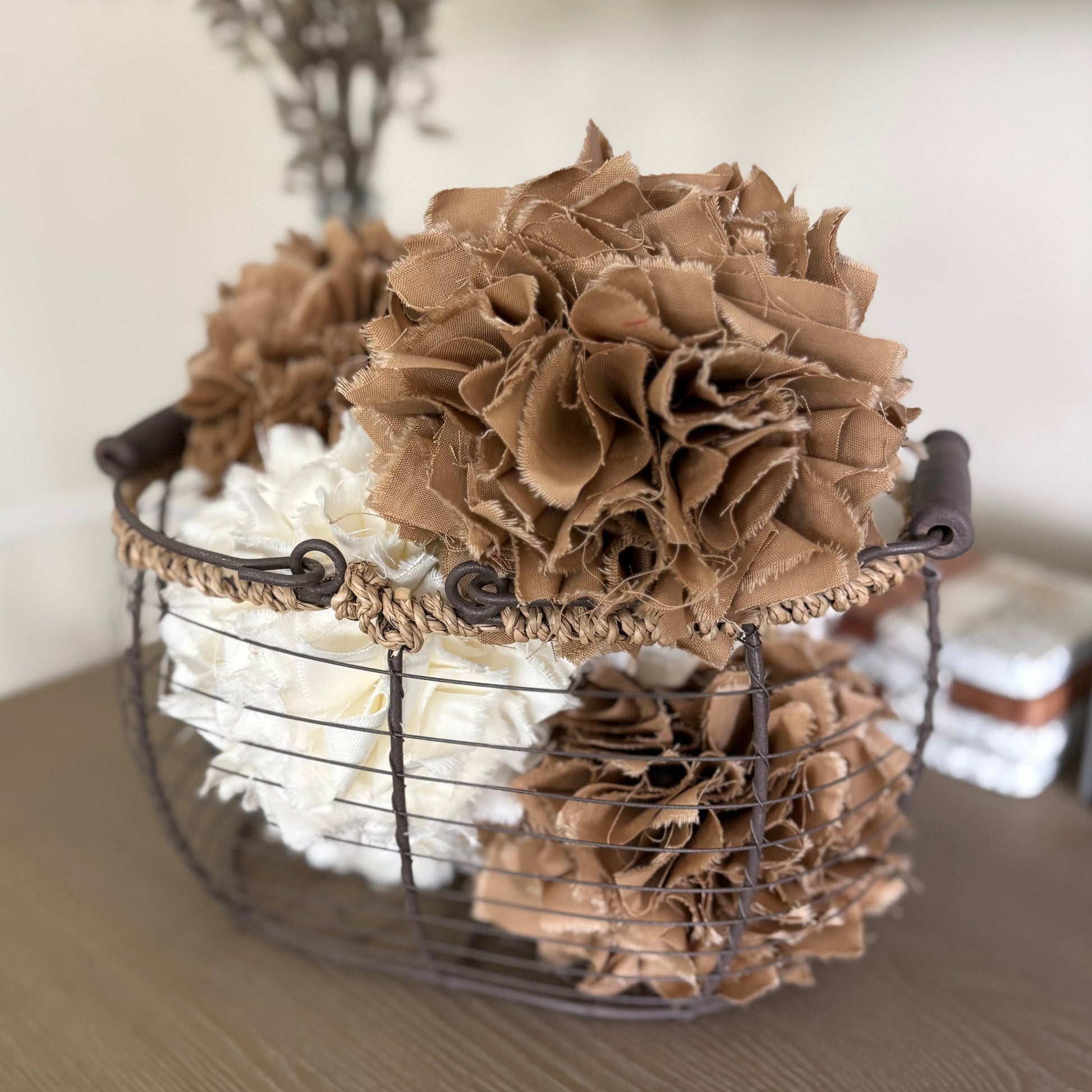 Decorative arrangement of brown textured rag balls  in a wire basket on a wooden surface.