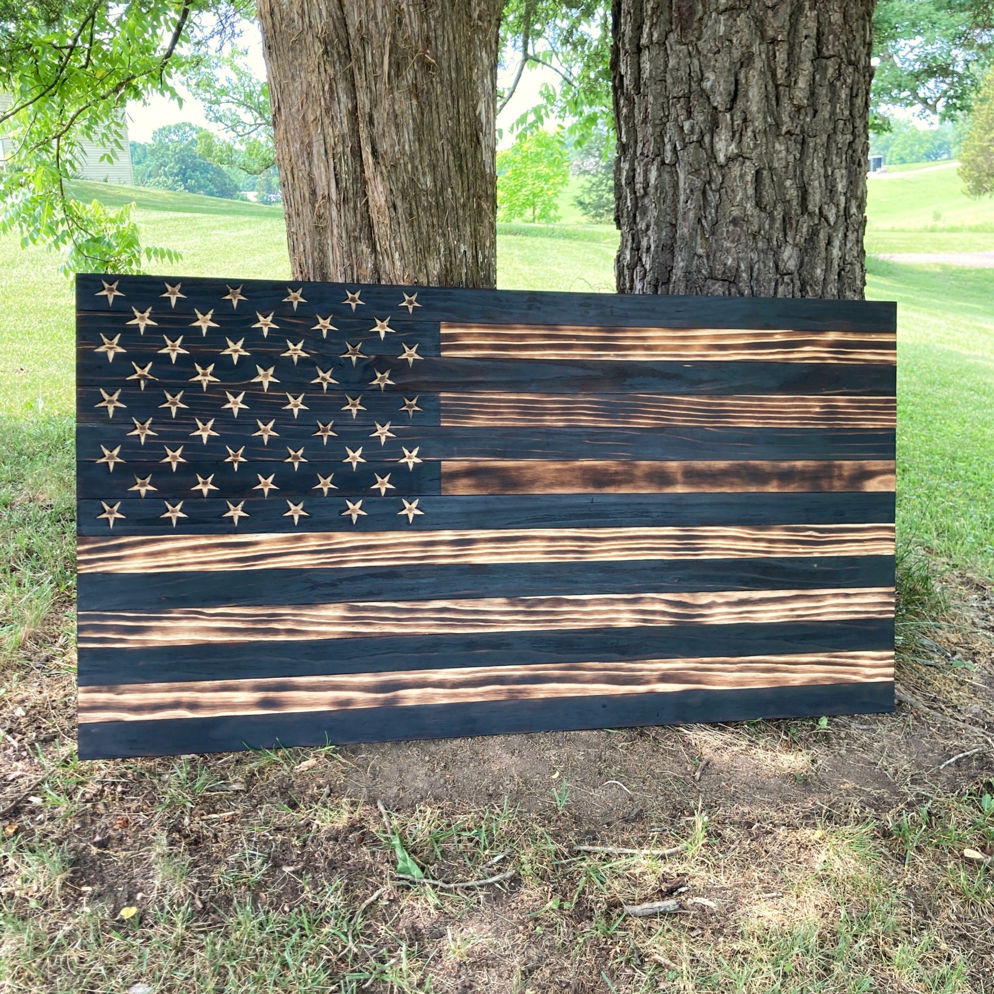 Five foot wide wooden American flag that has been burned to bring out the texture of the wood. No color just natural wood and carved stars in the union