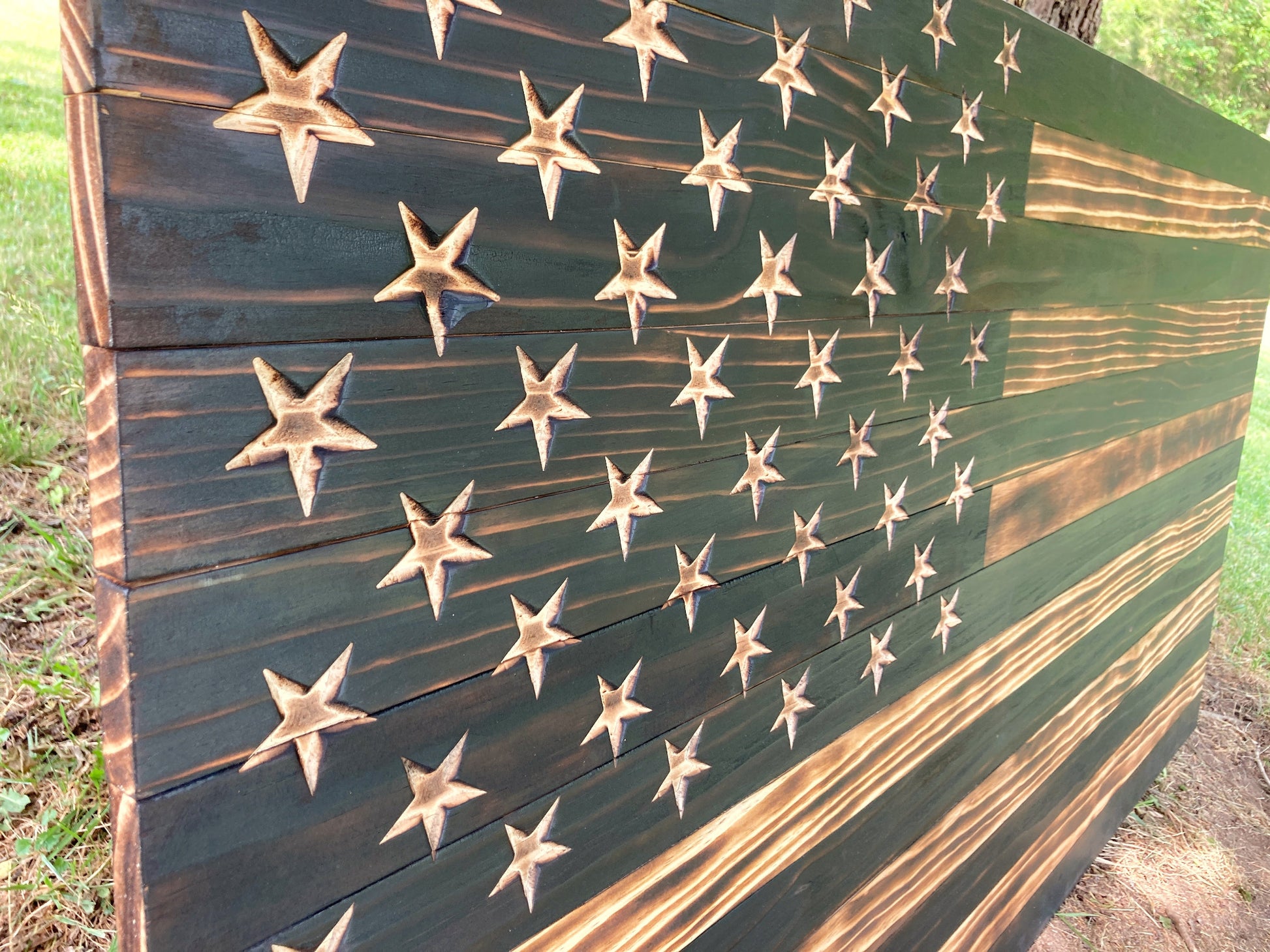 Close up of the carved stars in the union of the wooden American flag that has been burned to bring out the grain of the wood.