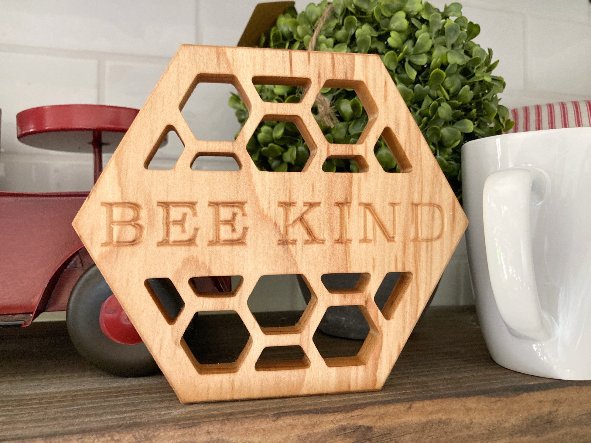 Solid maple wood honeycomb shaped trivet. Bee Kind is carved into the middle of the hot plate and surrounded by honeycomb cutouts